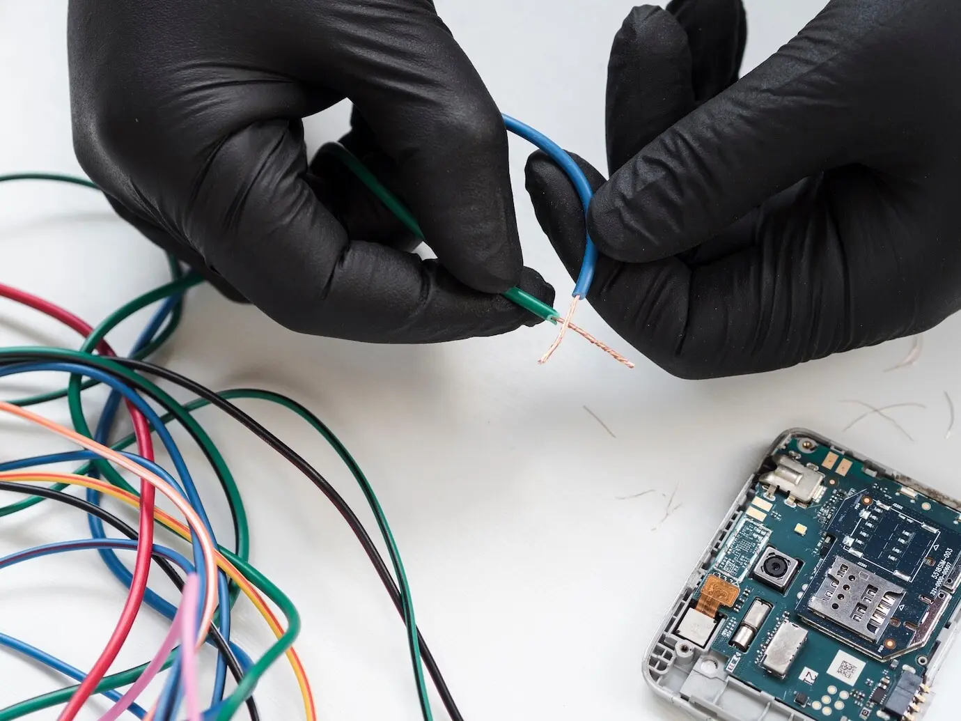 Hände mit schwarzen Handschuhen halten Verkabeltes.